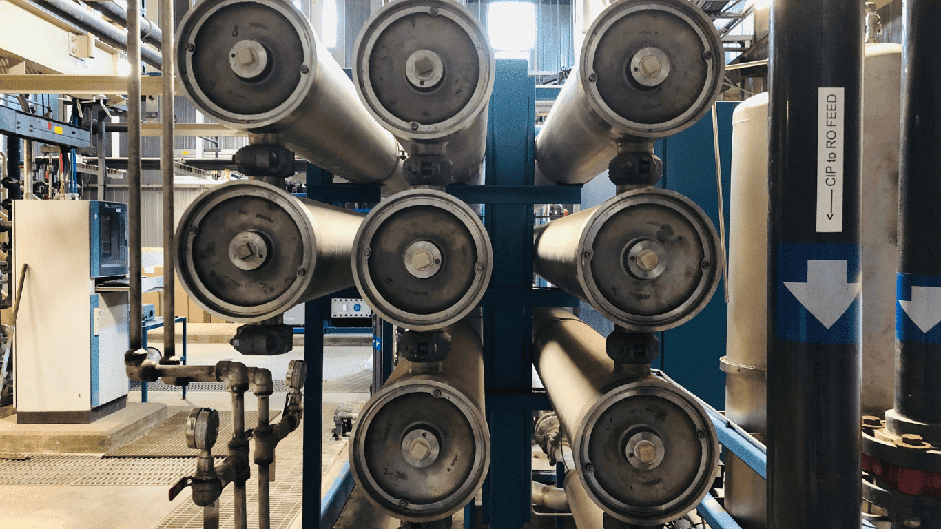 Reverse osmosis water filtration system shown in an industrial setting, featuring a high-capacity reverse osmosis system with multiple membrane housings used for advanced water treatment. This reverse osmosis filter setup demonstrates how reverse osmosis and modern osmosis systems work together to produce filtered water through reverse osmosis filtration. The image represents a reverse osmosis water filter and osmosis water filter designed to remove volatile organic compounds and contaminants, delivering clean drinking water with proven health benefits. A reverse osmosis system require proper installation, routine maintenance, and replacement filters to maintain performance and efficiency. This reverse osmosis water filtration system can support whole house applications, including a storage tank for consistent water supply, and works alongside water filters to improve overall water quality. Reverse osmosis filtration technology, commonly used by brands such as Express Water, ensures filtered water meets high standards for safety and taste in whole house systems.