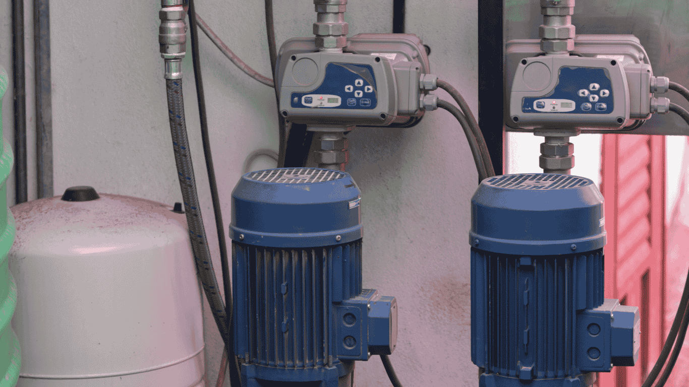 Industrial chlorine injection system installed as part of a chlorination system for municipal water systems and private well water treatment, featuring dual chlorine injection pump units mounted beside a pressure tank and water meter. This chlorine injection setup supports drinking water safety by delivering precise disinfection into the water supply, helping eliminate bacteria, iron, manganese, sediment, and odors that commonly affect water systems. The system is easily adjusted to regulate chlorine injection flow based on pressure and demand, ensuring accurate dosing for various applications in residential, commercial, and municipal environments.  The image shows two metering pump units connected to pipes that distribute treated water throughout the system, with a sealed tank for chemical storage and controlled injection. Designed for straightforward install and ongoing maintenance, the chlorine injection pump integrates with existing water systems to protect drinking water quality. During operation and maintenance, technicians use personal protective equipment to safely manage chemicals and ensure proper disinfection levels. This pump-based chlorination system introduces chlorine into the water supply, allowing air to vent appropriately while maintaining steady pressure and consistent flow for reliable, long-term water treatment performance.