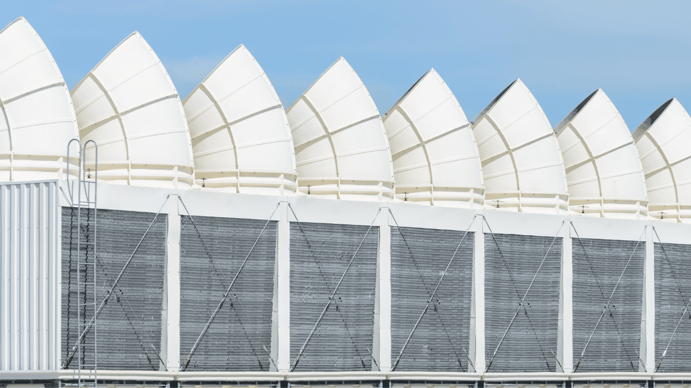 Large cooling tower with visible cooling tower parts including the fan deck, drift eliminators, and cooling tower nozzles, designed to manage efficient air flow across a crossflow tower structure. The tower's distribution system feeds water through nozzles into the distribution basin, while axial fans powered by a motor create mechanical draft to control pressure and airflow. Built from durable materials such as steel and wood, this setup reflects larger towers designed for both forced draft and natural wind interaction, with water collected in the water basin along the basin floor.