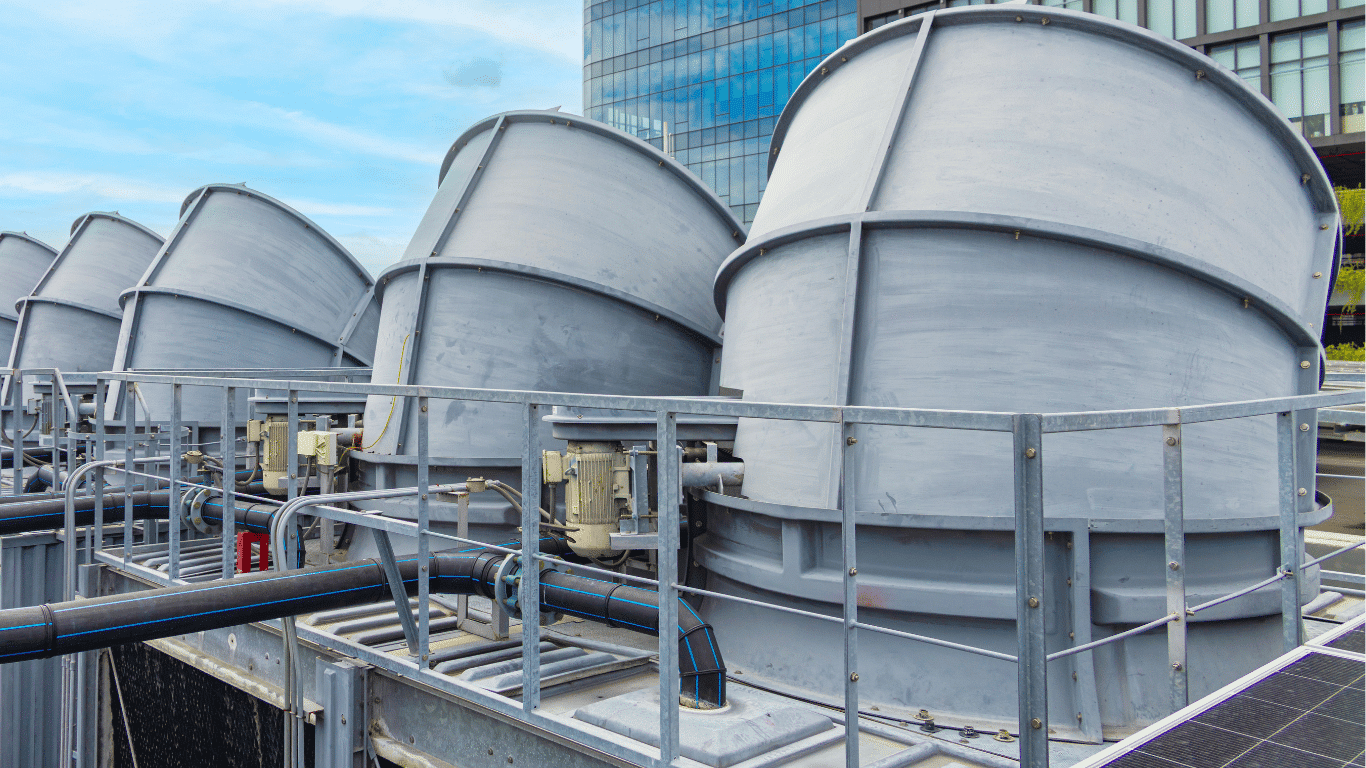 Large industrial natural draft cooling tower units at a facility, part of thermal power plants infrastructure, showing crossflow cooling towers, delta cooling towers, and a counterflow cooling tower system used in evaporative cooling towers. These draft cooling tower structures demonstrate cooling tower work, where hot water and warm water circulate while air flows vertically upward to reject heat and manage waste heat from thermal power stations and steel mills, supporting energy efficient operations with cool air, humid air, and visible exhaust air movement.