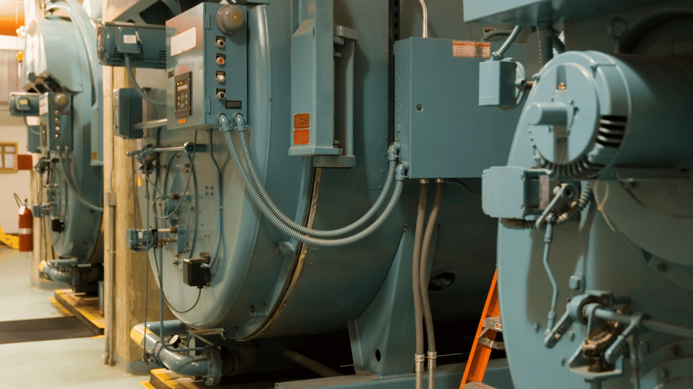Industrial boiler systems with advanced boiler water treatment chemicals in use, showing steam boilers, pipes, and equipment designed to maintain boiler efficiency and control corrosion. The image highlights boiler water, feed water, and condensate system components where chemical treatment and oxygen scavengers help prevent corrosion, scale formation, and deposits on metal surfaces. Properly treated boiler water improves water quality, reduces dissolved oxygen, dissolved solids, and carbon dioxide, and protects heating systems while minimizing energy costs and increase energy costs. This setup demonstrates boiler treatment, corrosion control, and testing processes using treatment chemicals like phosphate, sodium sulphate, and corrosion inhibitor solutions, along with water softeners and polymers for preventing scale and maintaining alkalinity, conductivity, and temperature in industrial boiler operation.