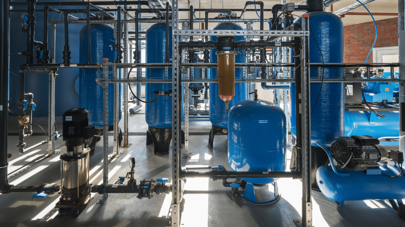 Industrial water softener system with blue filtration tanks, a resin tank, and a brine tank designed to treat hard water and improve water quality for whole house water softeners and commercial water supply systems. The water softening system uses ion exchange with resin beads to remove hardness minerals, calcium and magnesium ions, magnesium ions, calcium carbonate, and hard water minerals by replacing them with sodium ions from sodium chloride during the regeneration cycle. Salt based water softeners and salt based softeners help prevent scale buildup, limescale buildup, soap scum buildup, and soap scum on shower doors, water heaters, washing machines, and other water using appliances so water using appliances operate efficiently with consistent flow and stable water pressure. The treated water and softened water improve skin and hair, reduce dry skin, create softer skin, and help average household users save money on costly repairs and salt refills while supporting municipal water, city water, private well, and tap water treatment applications.