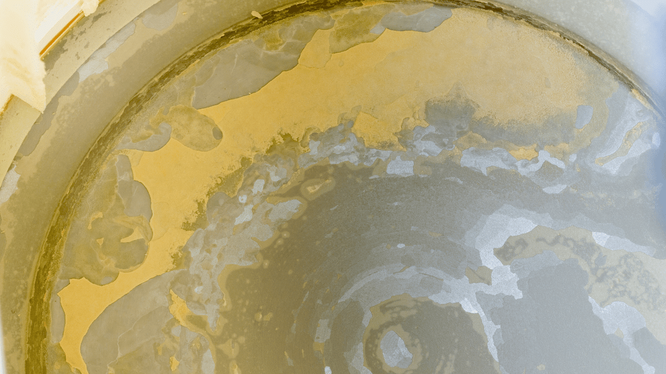Close-up of severe limescale and scale buildup inside an industrial water treatment system, showing white and yellow mineral deposits caused by hard water, excess calcium carbonate, calcium and magnesium, and other dissolved minerals accumulating on metal surfaces and pipes. The thick scale deposits and limescale build up can reduce equipment efficiency, restrict flow, and affect water using equipment, water heaters, and other appliances that regularly heat water and circulate hot water in commercial operations and industrial facilities.