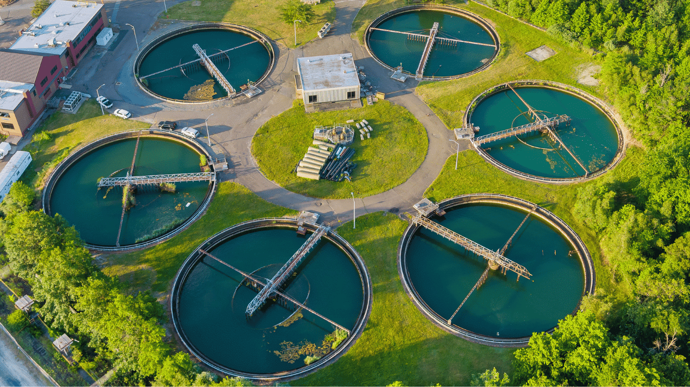 Aerial view of a modern wastewater treatment facility highlighting sustainable water management, proper water management, and proactive water management strategies designed to protect water resources and improve water quality. Large circular treatment systems support wastewater treatment, treated wastewater reuse, water recycling, and sustainable water practices that strengthen water supply, water availability, and water security during climate change and extreme drought conditions. The site demonstrates agricultural water management, groundwater resources protection, surface water conservation, drainage systems, leak detection, water budgeting, monitoring, and effective water management for managing water demand, water usage, water use, and water risks. Advanced technology, reverse osmosis, cooling water processes, and water efficient fixtures help prevent water waste, support toilet flushing systems, reduce flow rates, remove contaminants and heavy metals, and provide safe drinking water and clean water for communities, agriculture, food production, and ecosystem services while helping developed countries build resilience and achieve sustainability goals.
