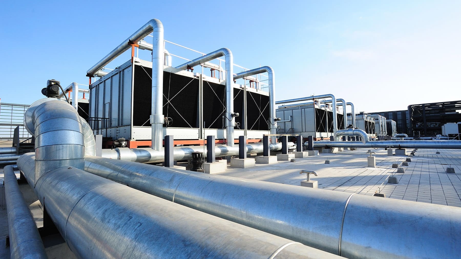 Industrial data center cooling systems with rooftop cooling towers, insulated piping, and heat exchangers supporting data center cooling applications. These cooling systems improve cooling efficiency, heat transfer efficiency, thermal efficiency, system performance, and energy efficiency while reducing energy consumption and supporting better power usage effectiveness and water usage effectiveness for AI data centers and modern data center operations.