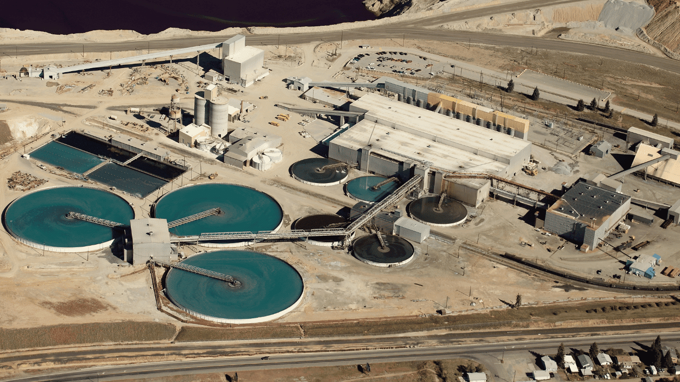Aerial view of a mine site featuring a wastewater treatment plant, circular clarifiers, process equipment, and water treatment systems supporting mining wastewater treatment. The facility manages mining wastewater, process water, suspended solids, and mining water to improve water quality, operational efficiency, and safe discharge while supporting mineral processing and tailings management.
