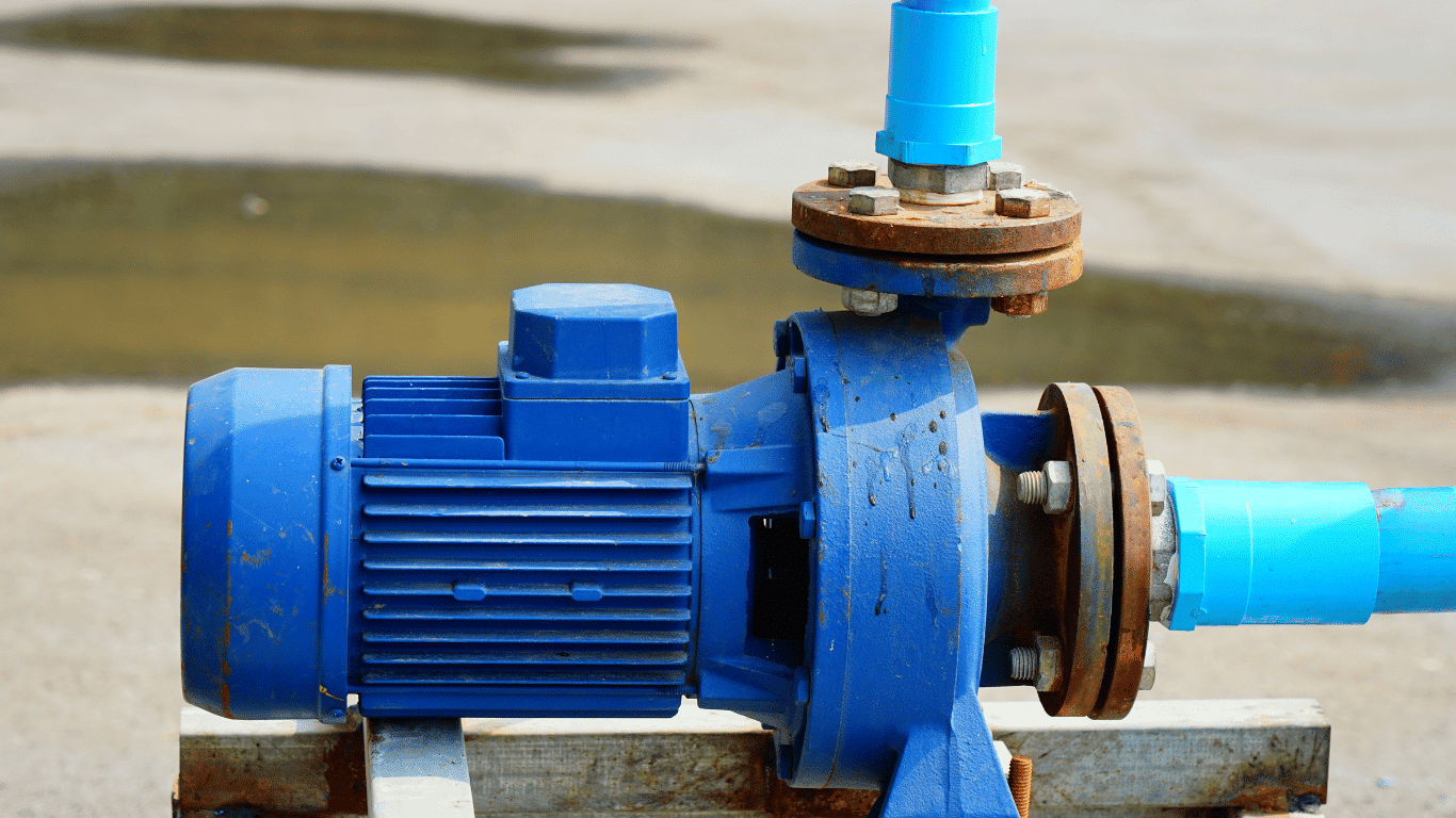 Blue industrial pump connected to PVC piping as part of a pH neutralization system for industrial wastewater treatment. The equipment supports continuous flow systems, flow through system operation, and pH adjustment systems that manage the pH neutralization process using a pH sensor, in tank pH sensor, and control panel. Typical installations use acid and caustic injection, sodium hydroxide, sulfuric acid, and calcium carbonate within treatment tanks or pH tanks to achieve pH adjustment, maintain effluent pH within the desired discharge range, and meet discharge pH limits vary across jurisdictions. The setup may include an automatic drain valve, automated drain valve, spring loaded injector valve, and metering pump sizing for accurate chemical dosing, while chemical usage optimization and system performance improvements help support regulatory compliance and reduce operating costs.