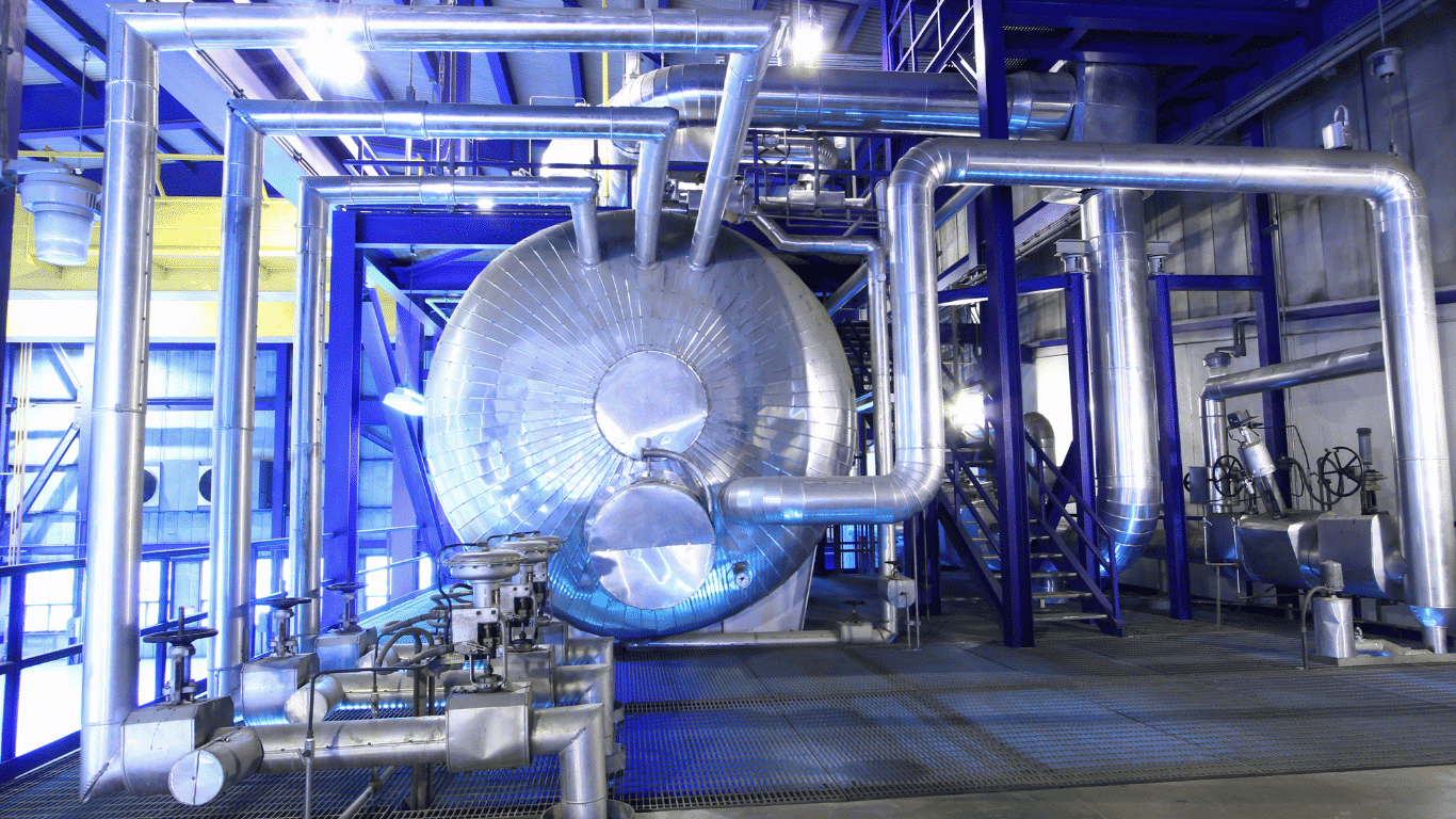 Industrial steam boiler water treatment equipment inside a modern boiler plant, showing insulated piping, a large boiler, and interconnected boiler systems designed for efficient operation. The setup supports boiler water treatment by conditioning boiler water and boiler feedwater with reverse osmosis, pre treatment, and water treatment processes. Proper water treatment helps improve heat transfer efficiency and overall energy efficiency while protecting boiler surfaces and metal surfaces from scale formation, corrosion, oxygen corrosion, and tube failure. The system manages dissolved oxygen, dissolved solids, suspended solids, calcium and magnesium ions, and other dissolved gases to maintain high quality water, extend equipment life, and support safe operation in high pressure boilers.