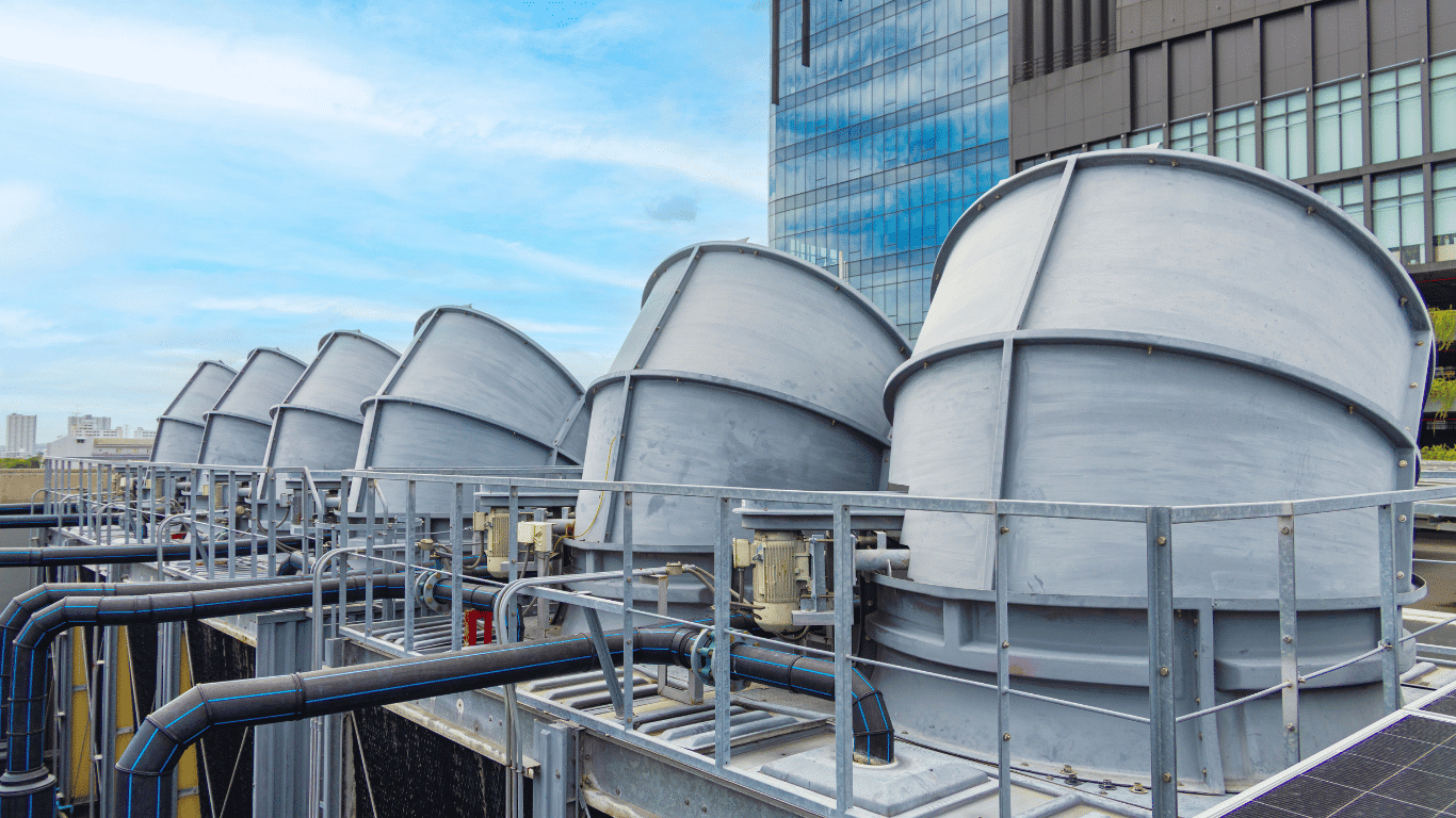 Commercial cooling towers and cooling tower systems on a rooftop, showing tower water piping and equipment used for cooling tower water systems and routine maintenance.