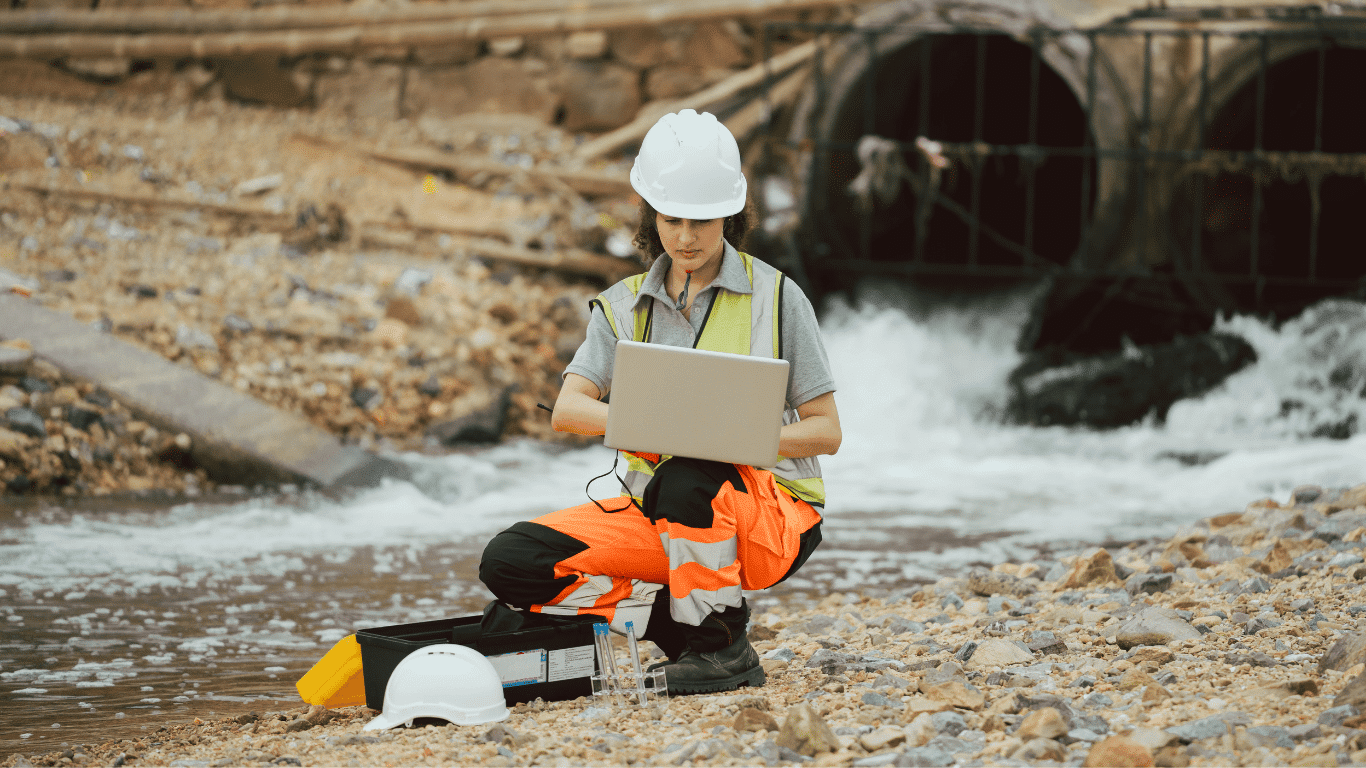 Industrial water quality monitoring system with a worker using a laptop and sensors to measure water quality, dissolved oxygen, temperature, flow rate, and other parameters.