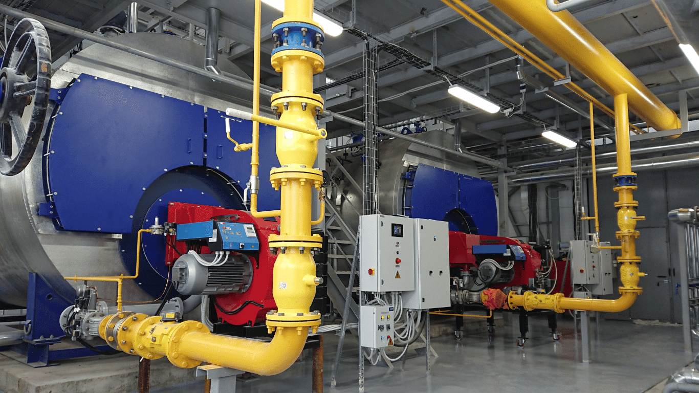 Industrial boiler water treatment system with yellow piping, steam boilers, control panels, boiler feed water, and monitoring equipment for efficient boiler system operation.