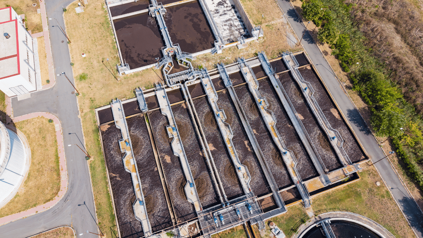 Aerial view of an industrial wastewater treatment plant with rectangular tanks and treatment systems processing oil and gas wastewater containing suspended solids and hydrocarbons.