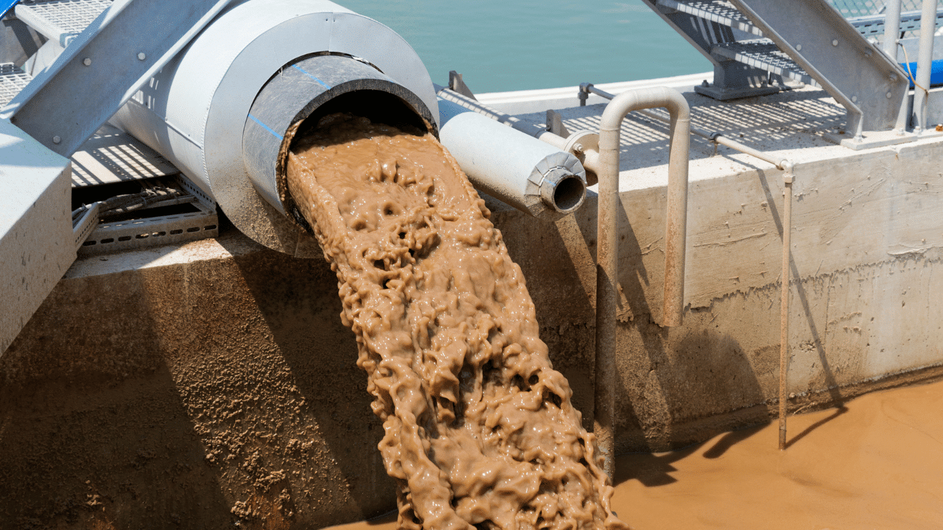 Industrial sludge dewatering equipment discharging biological sludge and waste sludge during wastewater treatment, showing the dewatering process, sludge particles, liquid separation, and treatment equipment used in sludge dewatering applications.