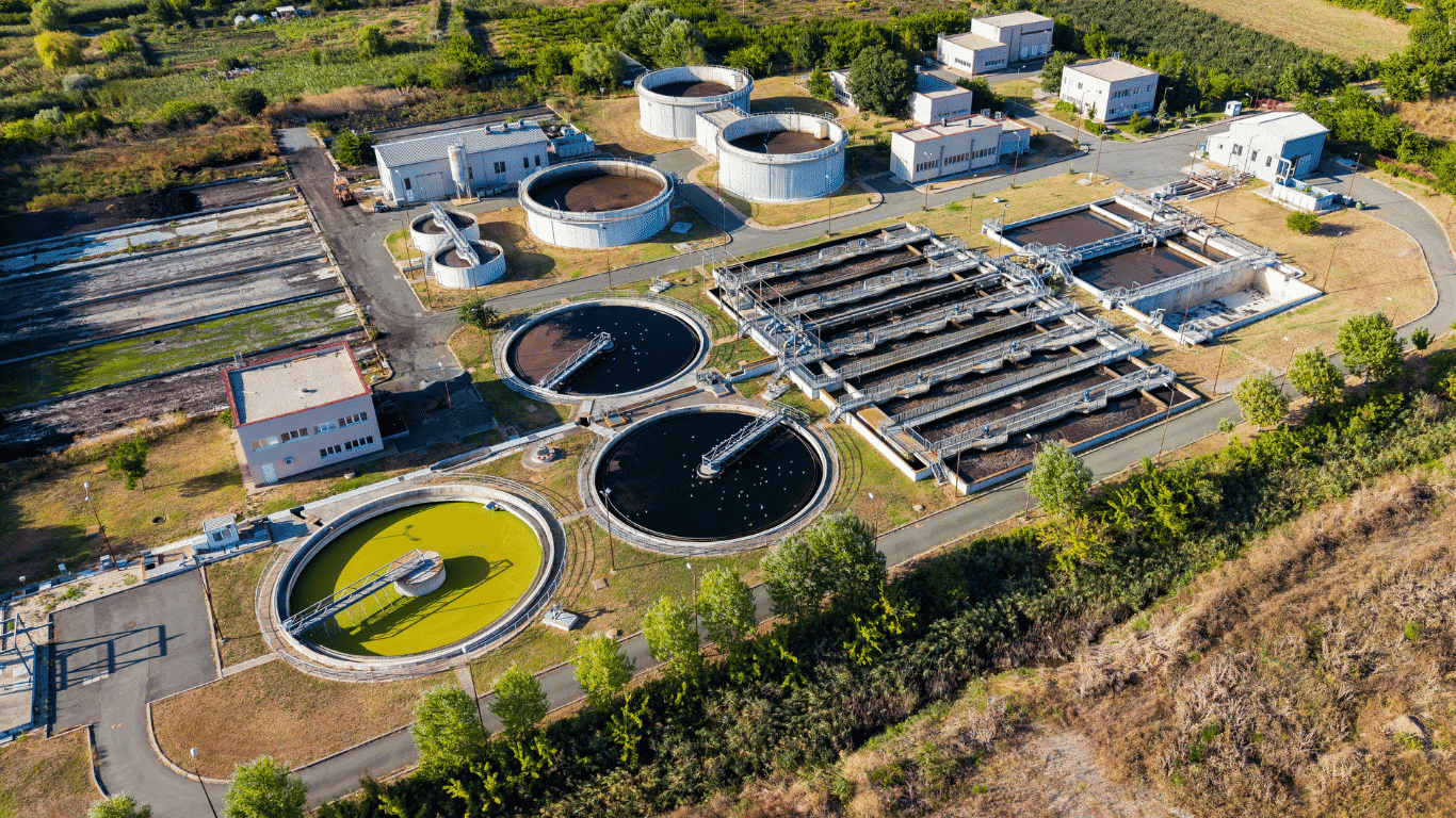 Aerial view of an industrial water treatment facility with circular treatment tanks, filtration basins, pipes, and water systems designed to support water quality and contaminant control.